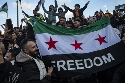 A demonstrator holds a Syrian opposition flag as members of the Syrian community chant slogans in Syntagma square in Athens to celebrate the end of the regime of Syrian dictator Bashar al-Assad after rebel fighters took control of the Syrian capital Damascus overnight, on December 8, 2024. Islamist-led rebels toppled Syria's longtime ruler Bashar al-Assad in a lightning offensive that a UN envoy called "a watershed moment" for the nation marred by civil war. (Photo by Angelos TZORTZINIS / AFP)Editoria: WARLocal: AthensIndexador: ANGELOS TZORTZINISSecao: armed conflictFonte: AFPFotógrafo: STF<!-- NICAID(15931111) -->