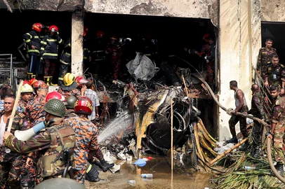 Bangladesh's fire service and security personnel conduct a search and rescue operation after an Air Force training jet crashed into school in Dhaka on July 21, 2025. At least 16 people, mostly students, were killed on July 21, when a training aircraft of the Bangladesh Air Force crashed into a school campus in the capital Dhaka, the government said. (Photo by Abdul Goni / AFP)<!-- NICAID(16084467) -->