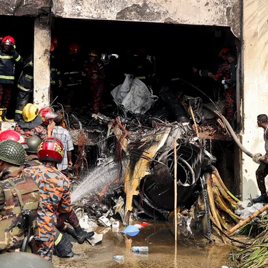 Bangladesh's fire service and security personnel conduct a search and rescue operation after an Air Force training jet crashed into school in Dhaka on July 21, 2025. At least 16 people, mostly students, were killed on July 21, when a training aircraft of the Bangladesh Air Force crashed into a school campus in the capital Dhaka, the government said. (Photo by Abdul Goni / AFP)<!-- NICAID(16084467) -->