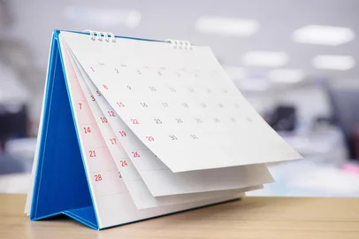 Calendar page flipping sheet on table with blurred office interior background business schedule planning appointment meeting concept. Fonte: 379597237<!-- NICAID(15721814) -->