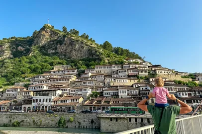 Father carries child piggyback on Gorica bridge in tourist town Berat in Albania, Europe. Footbridge crosses river Osum. UNESCO World Heritage Site with Ottoman architecture. City of thousand windowsPonte Gorica, em Berat, na AlbâniaFonte: 1038035812<!-- NICAID(16043847) -->