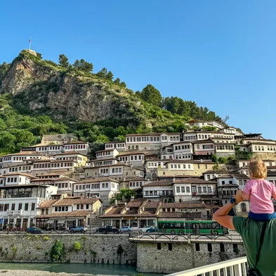 Father carries child piggyback on Gorica bridge in tourist town Berat in Albania, Europe. Footbridge crosses river Osum. UNESCO World Heritage Site with Ottoman architecture. City of thousand windowsPonte Gorica, em Berat, na AlbâniaFonte: 1038035812<!-- NICAID(16043847) -->