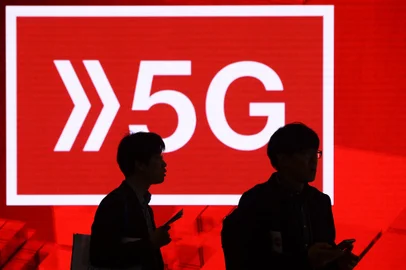 People walk past a 5G hotspot sign at the Mobile World Congress (MWC) in Barcelona on February 26, 2019. - Phone makers will focus on foldable screens and the introduction of blazing fast 5G wireless networks at the world's biggest mobile fair as they try to reverse a decline in sales of smartphones. (Photo by Josep LAGO / AFP)Editoria: FINLocal: BarcelonaIndexador: JOSEP LAGOSecao: telecommunication equipmentFonte: AFPFotógrafo: STR<!-- NICAID(14902915) -->