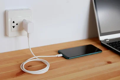 Plug in power outlet Adapter cord charger of smart phone on wooden floor<!-- NICAID(15789972) -->