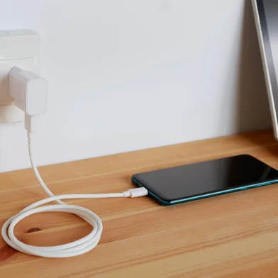 Plug in power outlet Adapter cord charger of smart phone on wooden floor<!-- NICAID(15789972) -->