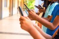 Close up shot, group of children hands busy using smartphone at school corridor - concept of social media, playing games, technology and education.<!-- NICAID(16100876) -->