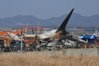 Firefighters and rescue personnel work near the wreckage of a Jeju Air Boeing 737-800 series aircraft after the plane crashed and burst into flames at Muan International Airport in South Jeolla Province, some 288 kilometres southwest of Seoul on December 29, 2024. A Jeju Air plane carrying 181 people from Bangkok to South Korea crashed on arrival December 29, colliding with a barrier and bursting into flames, with only two survivors rescued so far and 120 confirmed dead. (Photo by JUNG YEON-JE / AFP)<!-- NICAID(15944075) -->