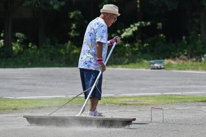 This photo taken on July 27, 2023 shows a senior citizen raking the pitch after playing the croquet-inspired game of "gateball" at a park in suburban Tokyo, as temperatures of 36C-plus (97F) scorched the Japanese capital. Japan is home to a legion of elderly devotees of the croquet-inspired game, and near-record heatwaves that have gripped the nation in recent weeks are nowhere near enough to convince them to stay cool at home. (Photo by Richard A. Brooks / AFP) / To go with 'JAPAN-WEATHER-SENIOR CITIZENS-GATEBALL,FOCUS' by Tomohiro OSAKIEditoria: SOILocal: TokyoIndexador: RICHARD A. BROOKSSecao: senior citizensFonte: AFPFotógrafo: STF<!-- NICAID(15543531) -->