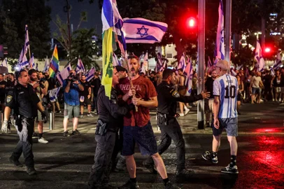 A demonstrator is restrained by an Israeli riot policeman during a protest rally against the Israeli government's judicial reform plan in Tel Aviv on July 24, 2023. Israeli lawmakers on July 24 approved a key clause of a controversial judicial reform plan that aims to curb the powers of the Supreme Court in striking down government decisions. (Photo by JACK GUEZ / AFP)<!-- NICAID(15492314) -->