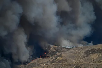 As chamas correm colina acima enquanto a coluna de fumaça do novo incêndio Hughes enche o céu em Castaic, um bairro noroeste de Los Angeles, Califórnia, em 22 de janeiro de 2025. Um novo incêndio florestal irrompeu ao norte de Los Angeles em 22 de janeiro, explodindo em tamanho e provocando milhares de ordens de evacuação em uma região já cambaleante pelos efeitos de grandes incêndios.<!-- NICAID(15959661) -->