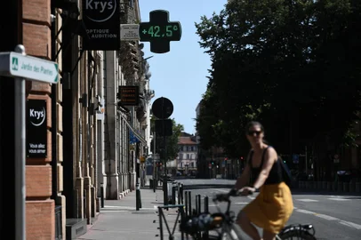 A local resident rides past a pharmacy sign displaying the temperature of 42,5°C in Toulouse, southern France, on July 17, 2022, as a heatwave hits France. - Fifteen departments, mostly on the western side of France, are placed under "red vigilance" as a heat wave hits the country and should reach its peak on July 18, 2022, announced on July 17, 2022 Meteo France. (Photo by Valentine CHAPUIS / AFP)<!-- NICAID(15151166) -->
