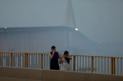 A couple walks at the Journalist Phelippe Daou bridge as smoke haze from fires in the Amazon rainforest blankets the area in Manaus, Amazonas State, northern Brazil, on October 13, 2023. Manaus, the main city in the Brazilian Amazon, has been suffocated since several days ago, when its two million inhabitants were engulfed by a toxic cloud formed by fires caused by "criminals", the environment ministry warned on Friday. (Photo by Michael Dantas / AFP)<!-- NICAID(15568839) -->
