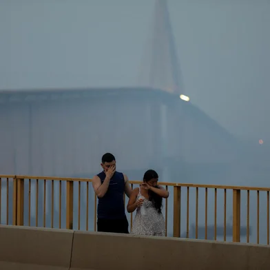 A couple walks at the Journalist Phelippe Daou bridge as smoke haze from fires in the Amazon rainforest blankets the area in Manaus, Amazonas State, northern Brazil, on October 13, 2023. Manaus, the main city in the Brazilian Amazon, has been suffocated since several days ago, when its two million inhabitants were engulfed by a toxic cloud formed by fires caused by "criminals", the environment ministry warned on Friday. (Photo by Michael Dantas / AFP)<!-- NICAID(15568839) -->