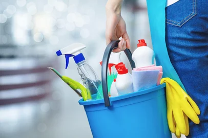 Cleaning lady holding a bucket of cleaning products in her hands .Cleaning lady holding a bucket of cleaning products in her hands on a blurred background.Fonte: 410499121<!-- NICAID(16266903) -->