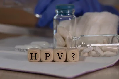 Abbreviation HPV with question mark for human papilloma virus infection composed of wooden dices. Pills, gynecological speculum, and laboratory technician in the background. CloseupIndexador: TOLICOVA ECATERINAFonte: 303865415<!-- NICAID(15226539) -->