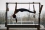 Fit female coach hanging hands and feet from the Pilates machine, woman working out on the Trapeze Table in a big Fitness Gym, big windows and street views. Pilates and healthy lifestyle conceptFonte: 419365360<!-- NICAID(15673409) -->