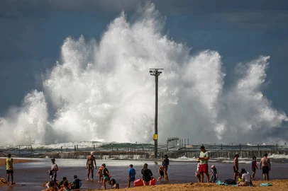 Families sit on North Narrabeen Beach as a wave breaks onto a rock pool in Sydney on April 18, 2025, as large swells hit the east coast of Australia. (Photo by DAVID GRAY / AFP)Editoria: WEALocal: SydneyIndexador: DAVID GRAYSecao: reportFonte: AFPFotógrafo: STF<!-- NICAID(16020681) -->
