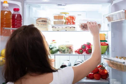 Rear View Of A Young Woman Taking Food From RefrigeratorIndexador: Andrey PopovFonte: 243008300<!-- NICAID(16330831) -->