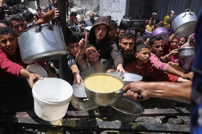 Displaced Palestinians gather to collect portions of cooked food at a charity distribution in Jabalia in the northern Gaza Strip on May 19, 2025. Prime Minister Benjamin Netanyahu said on May 19 that Israel will "take control" of the whole of Gaza, as the military pressed a newly intensified campaign in the war-ravaged territory. After Israel announced it would let limited aid into Gaza, the head of the World Health Organization issued a stark warning on the humanitarian crisis in the territory, saying that "two million people are starving". (Photo by Bashar TALEB / AFP)Editoria: WARLocal: JabaliaIndexador: BASHAR TALEBSecao: warFonte: AFPFotógrafo: STR<!-- NICAID(16040715) -->