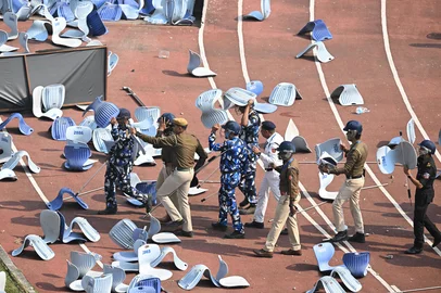 Security personnel shield themselves with chairs whilst the crowd reacts as Inter Miami's Argentine forward #10 Lionel Messi departs from the Salt Lake Stadium in Kolkata on December 13, 2025. Thousands of fans packed into a stadium in eastern India on December 13 to cheer on Lionel Messi as the football legend unveiled a 21-metre (70-foot) statue of himself. (Photo by Dibyangshu SARKAR / AFP)Editoria: SPOLocal: KolkataIndexador: DIBYANGSHU SARKARSecao: soccerFonte: AFPFotógrafo: STR<!-- NICAID(16186263) -->