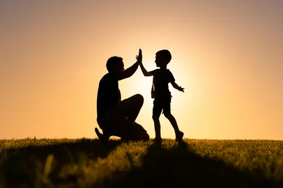Pai e filho batendo as mãos no por do sol<!-- NICAID(15984461) -->