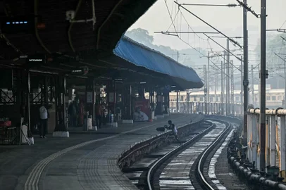 A passenger walks across a railway track at the New Delhi railway station in New Delhi on February 16, 2025. At least 15 people died during a stampede at a railway station in India's capital late on February 15 when surging crowds scrambled to catch trains to the world's largest religious gathering, a medical official told AFP. (Photo by Sajjad HUSSAIN / AFP)<!-- NICAID(15977318) -->