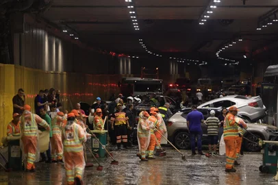 MIGUEL SCHINCARIOL / AFP Funcionários municipais limpam lama e destroços ao redor de veículos imobilizados e de um ônibus articulado dentro do túnel do Anhangabaú após fortes chuvas em São Paulo, Brasil, em 14 de outubro de 2026. <!-- NICAID(16387656) -->