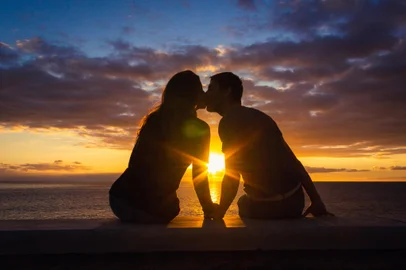duas pessoas se beijando no por do sol<!-- NICAID(15845206) -->