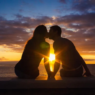 duas pessoas se beijando no por do sol<!-- NICAID(15845206) -->