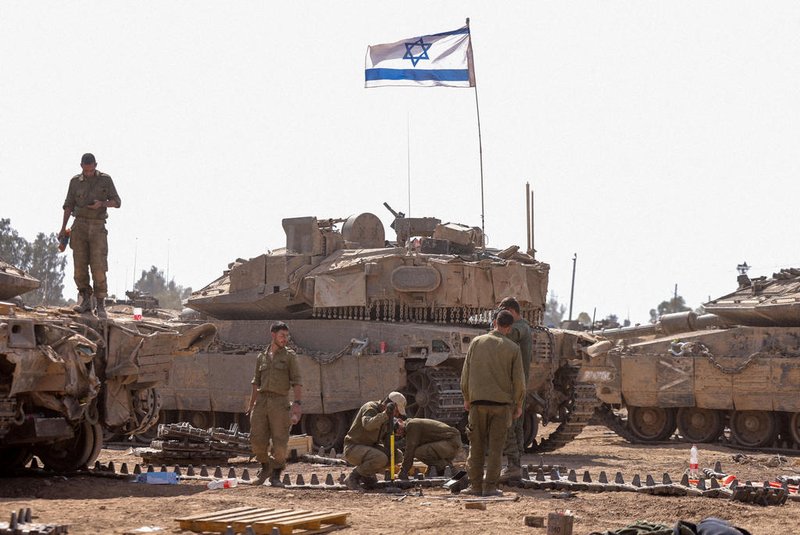 Israeli soldiers work on their tanks in a army camp near Israel's border with the Gaza Strip on April 8, 2024, amid the ongoing conflict between Israel and the militant group Hamas. (Photo by Menahem KAHANA / AFP)<!-- NICAID(15729232) -->