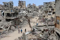 -- AFP PICTURES OF THE YEAR 2024 --Palestinians walk on a dirt road lined with rubble from destroyed buildings in the Shujaiya neighbourhood of Gaza City on October 7, 2024, on the first anniversary of the ongoing war in the Gaza Strip between Israel and the Palestinian Hamas group. (Photo by Omar AL-QATTAA / AFP) / AFP PICTURES OF THE YEAR 2024<!-- NICAID(15933359) -->