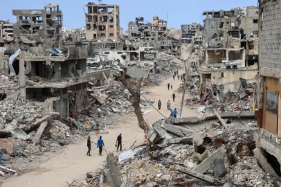 -- AFP PICTURES OF THE YEAR 2024 --Palestinians walk on a dirt road lined with rubble from destroyed buildings in the Shujaiya neighbourhood of Gaza City on October 7, 2024, on the first anniversary of the ongoing war in the Gaza Strip between Israel and the Palestinian Hamas group. (Photo by Omar AL-QATTAA / AFP) / AFP PICTURES OF THE YEAR 2024<!-- NICAID(15933359) -->