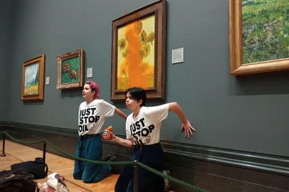 A handout picture from the Just Stop Oil climate campaign group shows activists with their hands glued to the wall under Vincent van Gogh's "Sunflowers" after throwing tomato soup on the painting at the National Gallery in central London on October 14, 2022. - London's Metropolitan Police said its officers arrested two protesters from the Just Stop Oil group for criminal damage and aggravated trespass after they "threw a substance over a painting" at the gallery on Trafalgar Square. (Photo by Handout / Just Stop Oil / AFP) / RESTRICTED TO EDITORIAL USE - MANDATORY CREDIT "AFP PHOTO /  JUST STOP OIL " - NO MARKETING - NO ADVERTISING CAMPAIGNS - DISTRIBUTED AS A SERVICE TO CLIENTSEditoria: ACELocal: LondonIndexador: HANDOUTSecao: weather scienceFonte: Just Stop OilFotógrafo: Handout<!-- NICAID(15235565) -->