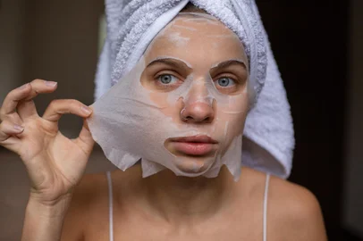 Beauty portrait woman with a towel wrapped around her head taking off sheet maskFonte: 549485757<!-- NICAID(15687763) -->