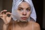 Beauty portrait woman with a towel wrapped around her head taking off sheet maskFonte: 549485757<!-- NICAID(15687763) -->