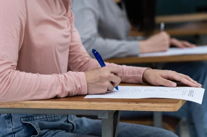 Young female university students concentrate on doing examination in classroom. Girl students seriousely writes the exercise of the examinations in the classroom.Indexador: SC PHOTHOGRAPHFonte: 409561264<!-- NICAID(15485468) -->