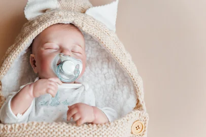Reborn a boy doll with a pacifier sleeps in a knitted beige envelope. Copy spaceReborn a boy doll with a pacifier sleeps in a knitted beige envelope. Copy space.Fonte: 485817674<!-- NICAID(16026702) -->