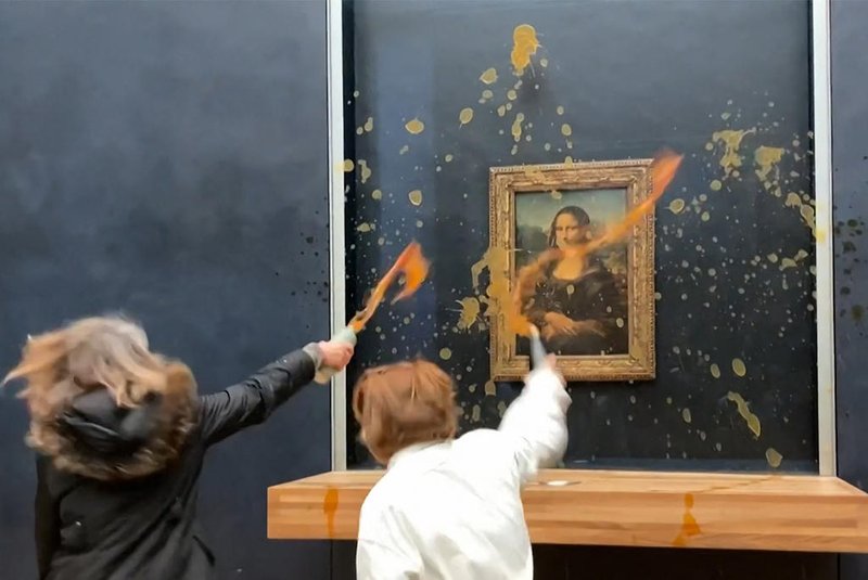 This image grab taken from AFPTV footage shows two environmental activists from the collective dubbed "Riposte Alimentaire" (Food Retaliation) hurling soup at Leonardo Da Vinci's "Mona Lisa" (La Joconde) painting, at the Louvre museum in Paris, on January 28, 2024. Two protesters on January 38, 2024 hurled soup at the bullet-proof glass protecting Leonardo da Vinci's "Mona Lisa" in Paris, demanding the right to "healthy and sustainable food", an AFP journalist said. It is the latest attack on the masterpiece in the French capital's Louvre museum, after someone threw a custard pie at it in May 2022, but it's thick glass casing ensured it came to no harm. (Photo by David CANTINIAUX / AFPTV / AFP)<!-- NICAID(15662692) -->