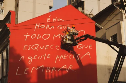 A artista plástica Mana Bernardes desembarcou em Porto Alegre trazendo seus manuscritos à cidade em forma de duas empenas. Mana, conhecida por seu trabalho social e artístico e por suas metodologias de economia criativa, pintou dois murais em parceria com o projeto “Paredes com Propósito” a convite do Instituto Mari Johannpeter. A iniciativa busca oferecer à cidade um respiro de poesia após as enchentes que impactaram profundamente a vida de milhares de pessoas.Localizado na Rua dos Andradas, 659, o primeiro mural tem uma frase inédita, criada pela artista em resposta à catástrofe recente<!-- NICAID(15919097) -->