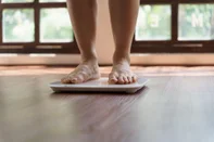 Fat diet and scale feet standing on electronic scales for weight control. Measurement instrument in kilogram for a diet control.Fonte: 657229185<!-- NICAID(15833944) -->