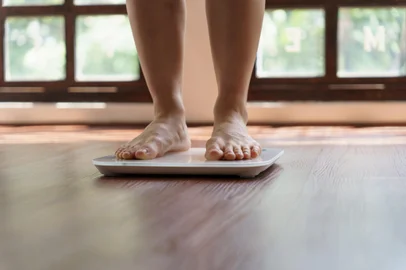 Fat diet and scale feet standing on electronic scales for weight control. Measurement instrument in kilogram for a diet control.Fonte: 657229185<!-- NICAID(15833944) -->