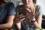 Couple customers holding mobile phone using smartphone apps, cloPostar ou não foto com o namorado. Foto:  / stock.adobe.comFonte: 216815724<!-- NICAID(15040991) -->