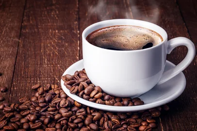 Xícara de café preto. Grãos de café ao redor<!-- NICAID(15186177) -->
