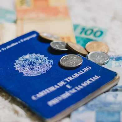 Carteira de trabalho com dinheiro referente ao pagamento do salário do funcionário.<!-- NICAID(15198096) -->