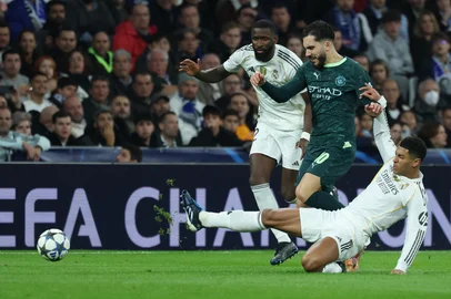 Manchester City's French midfielder #10 Ryan Cherki (C) vies for the ball with Real Madrid's English midfielder #05 Jude Bellingham during the UEFA Champions League league phase day 6 football match between Real Madrid CF and Manchester City at Santiago Bernabeu Stadium in Madrid on December 10, 2025. (Photo by Thomas COEX / AFP)<!-- NICAID(16184301) -->