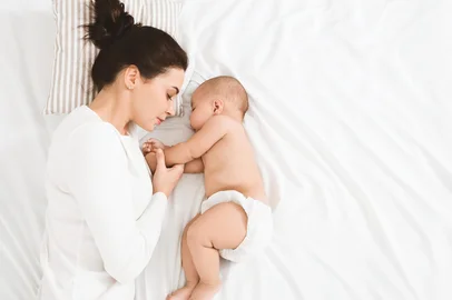 Bedtime. Adorable baby sleeping with his mother in bed, touching hands, top view, copy space. <!-- NICAID(16048333) -->