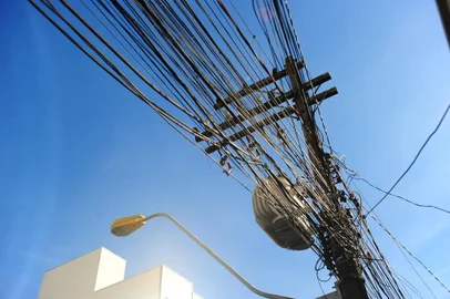 CAXIAS DO SUL, RS, BRASIL, 23/05/2023. O centro de Caxias do Sul vai receber, em 1º de junho, a terceira força-tarefa para a remoção de fios quebrados ou fora de uso. O trabalho está programado para ocorrer na Rua Tronca, a partir do cruzamento com a Rua Alfredo Chaves, no bairro Exposição. O trecho que integra o quadrilátero demarcado para a primeira fase da ação. Na foto, imagens de fios e emaranhados em postes de energia elétrica na rua Tronca com Alfredo Chaves. (Porthus Junior/Agência RBS)<!-- NICAID(15436215) -->