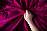 Woman hand on the silk bedding, sex and orgasm concept<!-- NICAID(15809320) -->