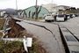People stand next to large cracks in the pavement after evacuating into a street in the city of Wajima, Ishikawa prefecture on January 1, 2024, after a major 7.5 magnitude earthquake struck the Noto region in Ishikawa prefecture in the afternoon. Tsunami waves over a metre high hit central Japan on January 1 after a series of powerful earthquakes that damaged homes, closed highways and prompted authorities to urge people to run to higher ground. (Photo by Yusuke FUKUHARA / Yomiuri Shimbun / AFP) / Japan OUT / NO ARCHIVES - MANDATORY CREDIT: Yomiuri Shimbun<!-- NICAID(15638348) -->
