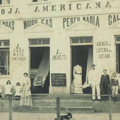 Antiga Loja Americana, de propriedade de Annunccio Ungaretti, na Av. Júlio de Castilhos, entre Dr. Montaury e Visconde de Pelotas. Fachada da Americana destaca os produtos e serviços oferecidos em 1911, entre eles o comércio de fazendas, miudezas, perfumaria e até semente de hortaliças. O estabelecimento abrigava ainda a Agência da Loteria do Estado. Imagem integra a mostra CDL Presente, comemorativa aos 50 anos da entidade fundada em 1965.<!-- NICAID(11265324) -->